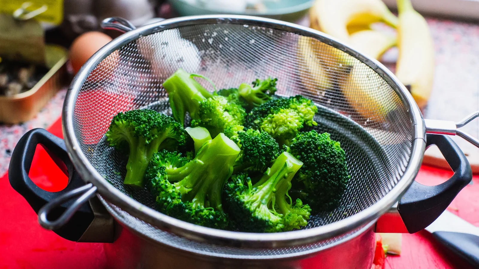 Fresh broccoli in a steel strainer on a stove