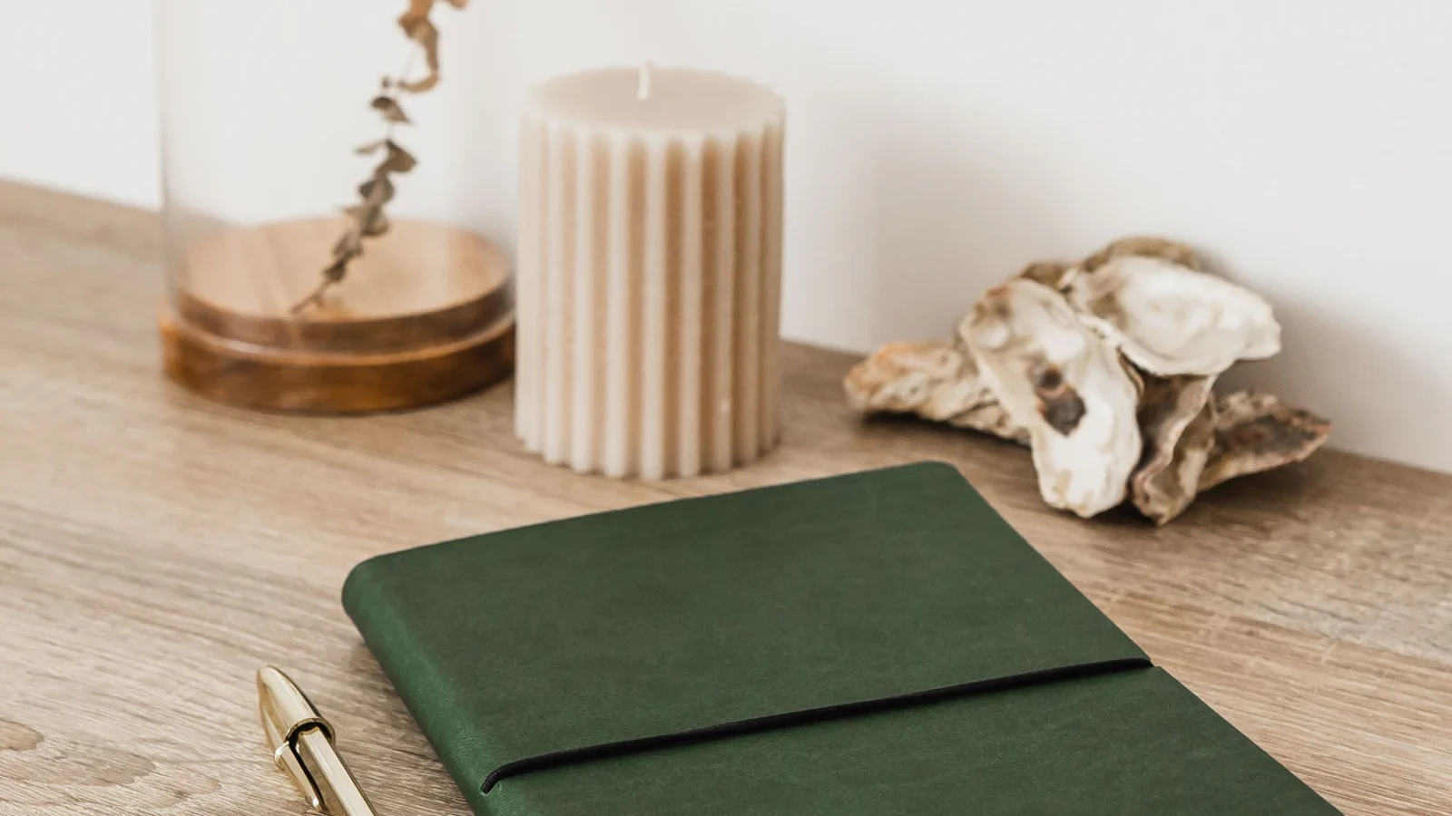 Green notebook with a pen on a wooden desk